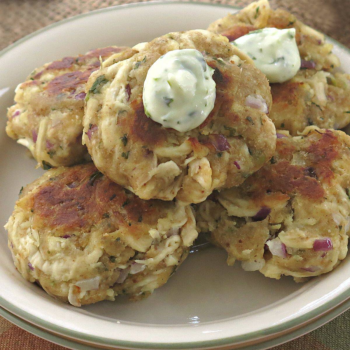 Five Tuscan chicken cakes on a plate topped with aioli.