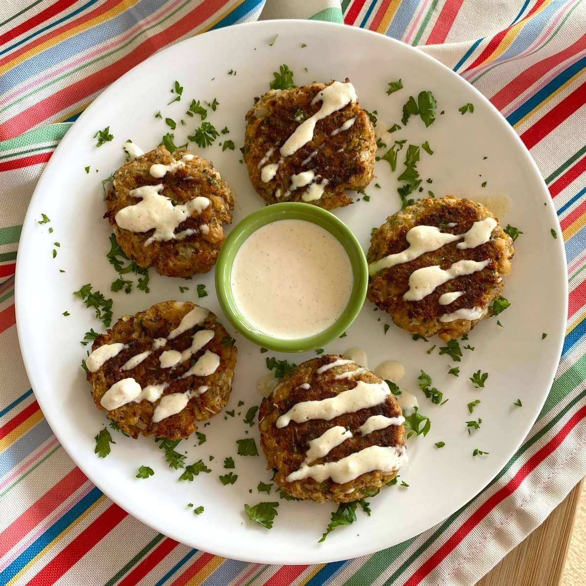 Five salmon cakes on a white plate.