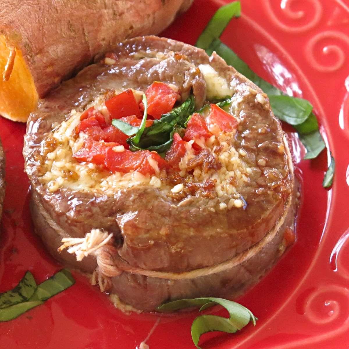 Flank steak pinwheel on a red plate.