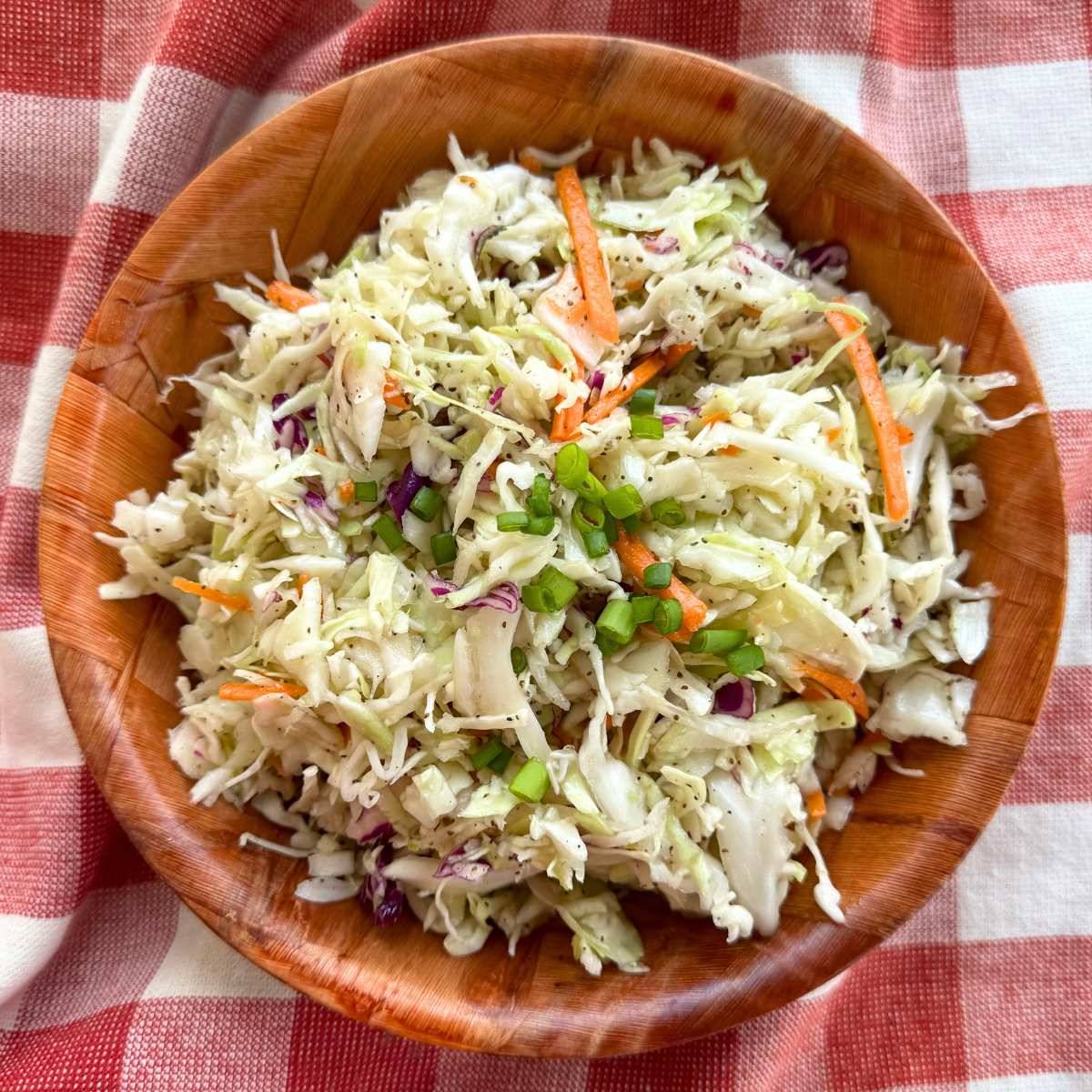 Coleslaw with vinegar dressing in brown bowl.