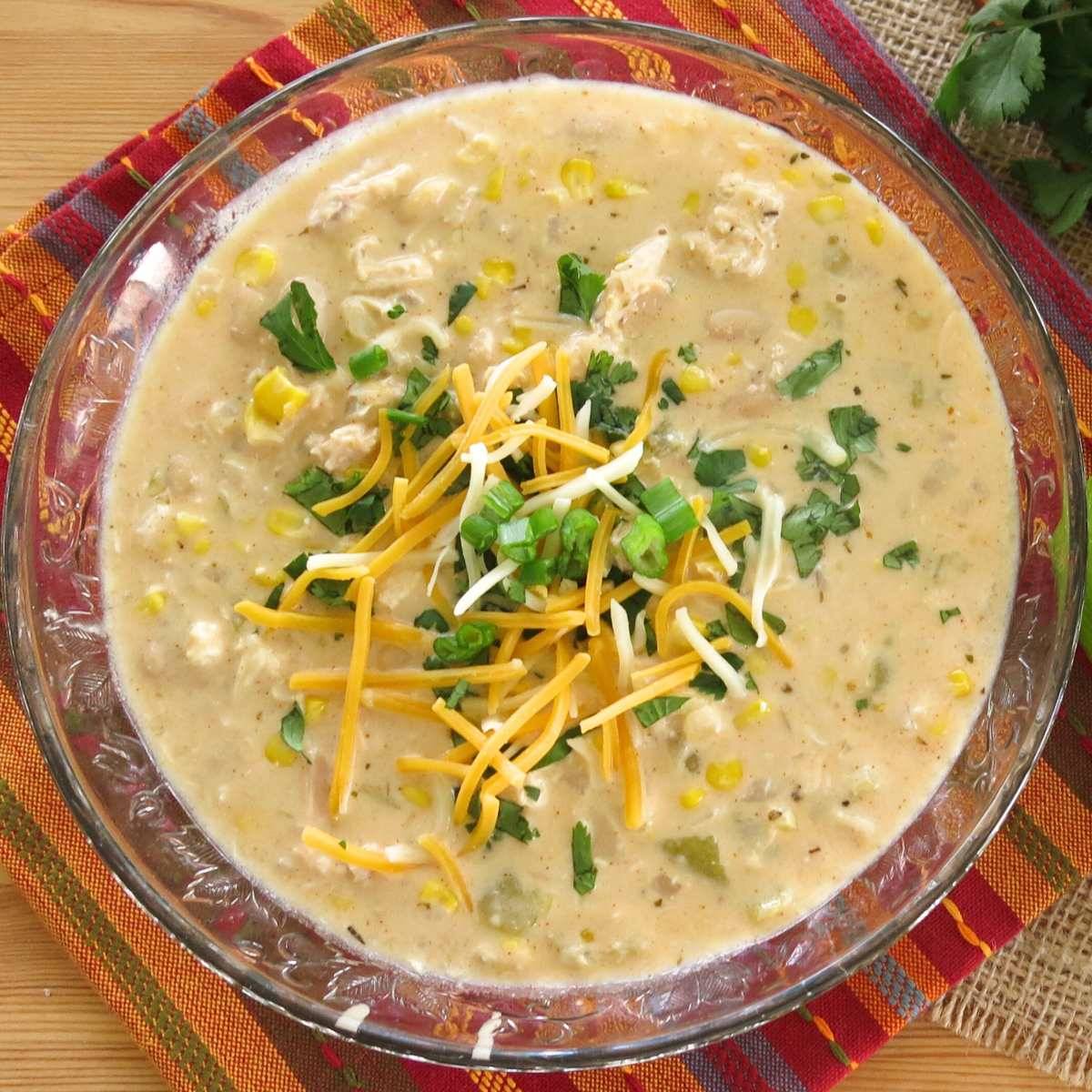 White chicken chili in a glass bowl over a colorful orange napkin.