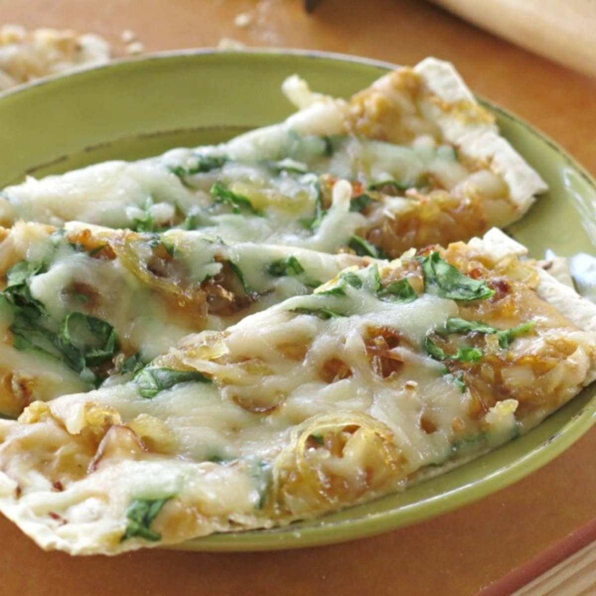 Two slices of pumpkin flatbread pizza on a green plate.