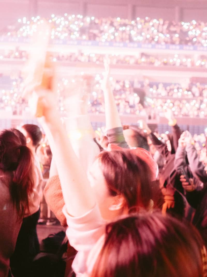 A crowd of people at a concert with their arms in the air