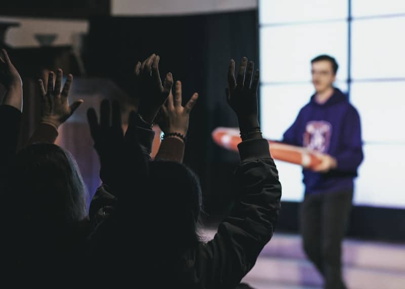 People raising hands towards a man holding a skateboard