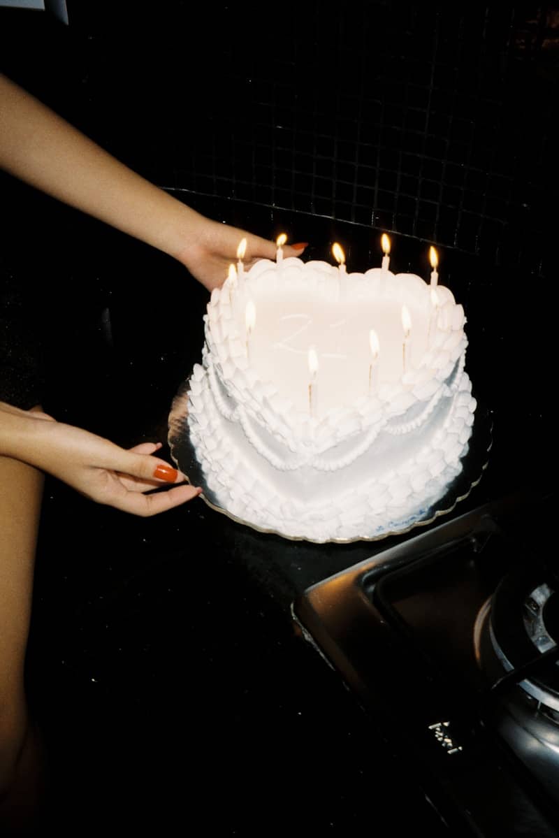 Heart-shaped cake with lit candles being held