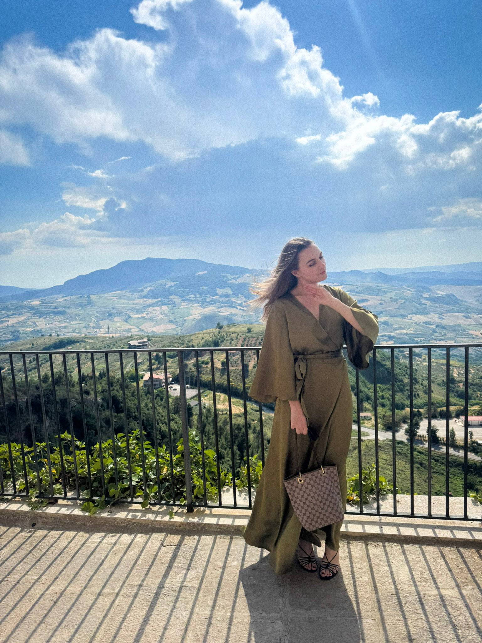 A woman standing next to a hillside church in Sicily. 