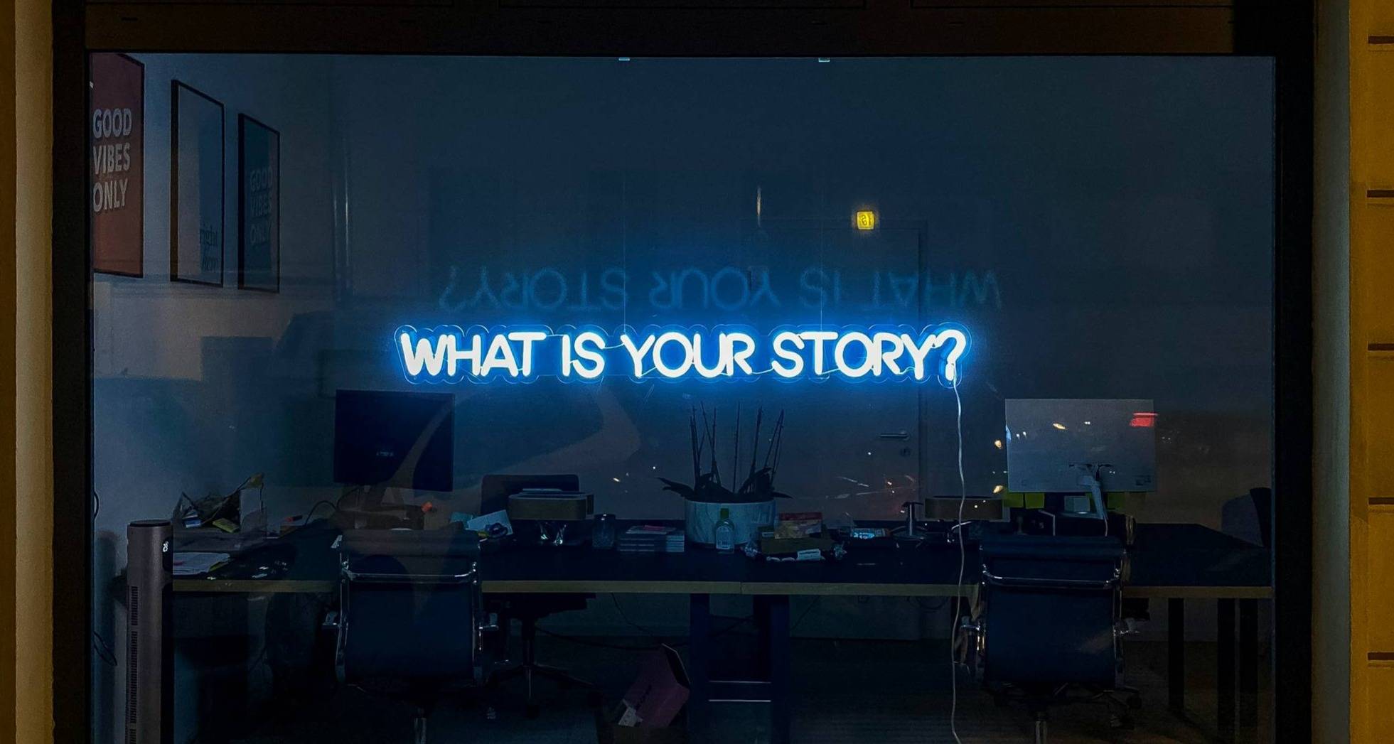 The words "What is your story?" shine in blue neon on a dark storefront window.