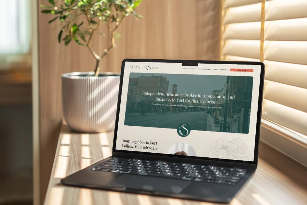 laptop on a desk, open to Shanti Insurance Services