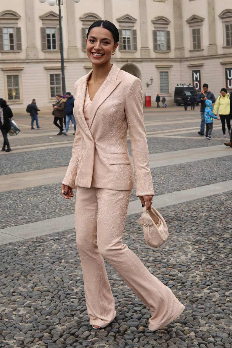 A woman in a pink suit walking down a street