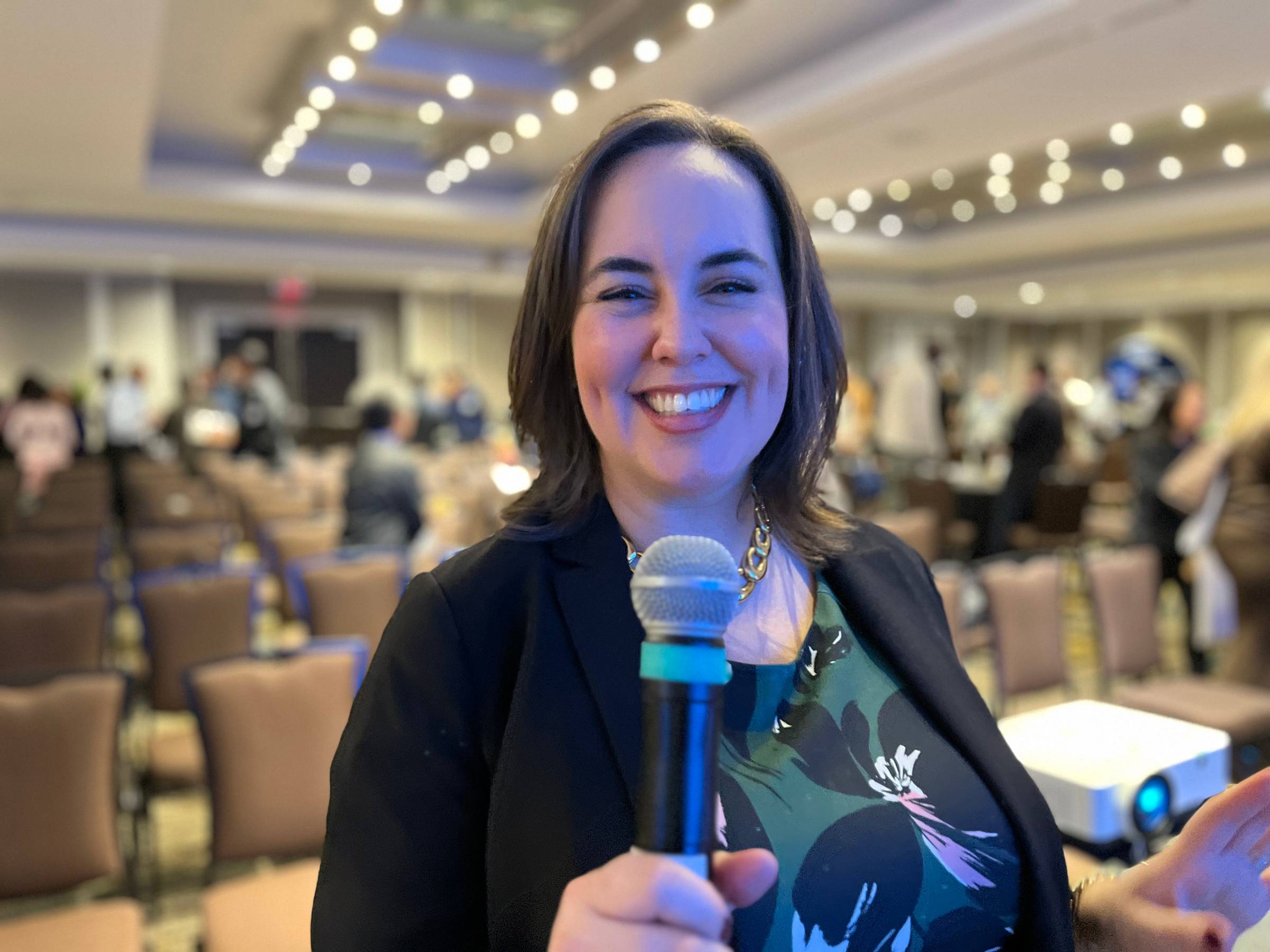 Trina smiling and holding a microphone at a speaking event in Toronto