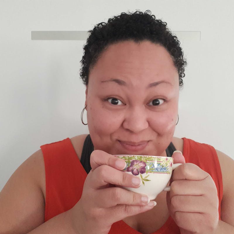 Profile photo of Tiana Dodson, a brown-skinned person with short, dark, curly hair holding a teacup and smiling.