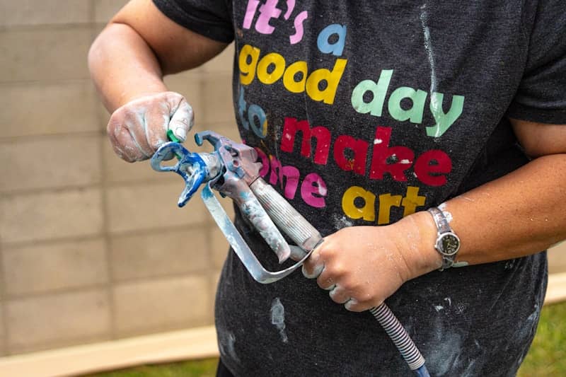 Someone holds a paint sprayer.