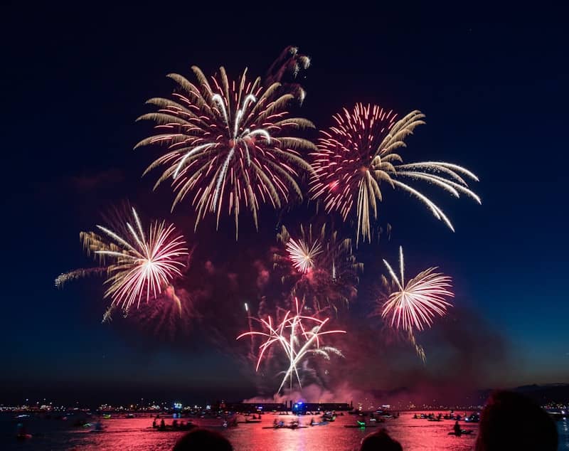 A group of people watching fireworks on the water