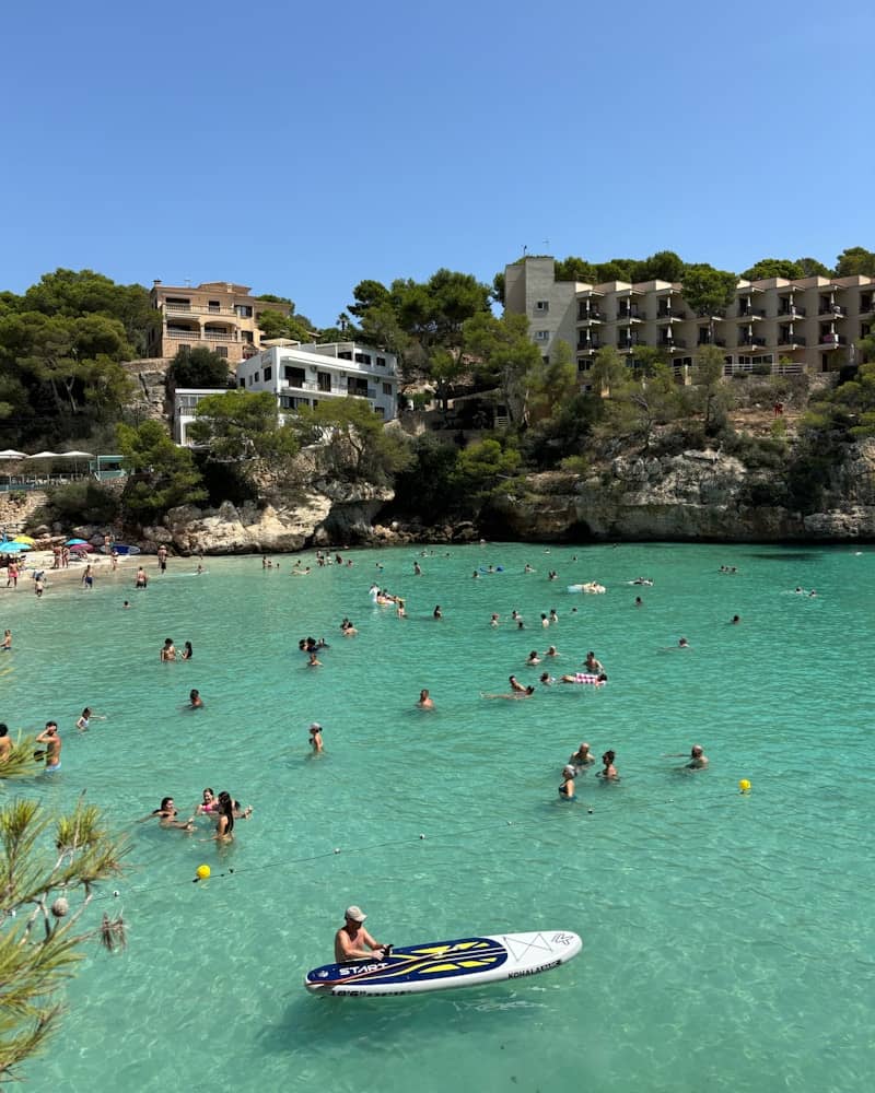 People swimming and relaxing in a clear turquoise bay.