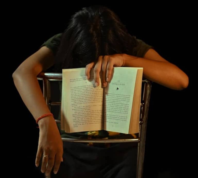 Person resting head on open book