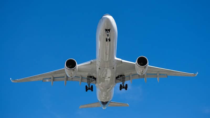 Airplane flying overhead against a clear blue sky. BlackBird Finance Newsletter