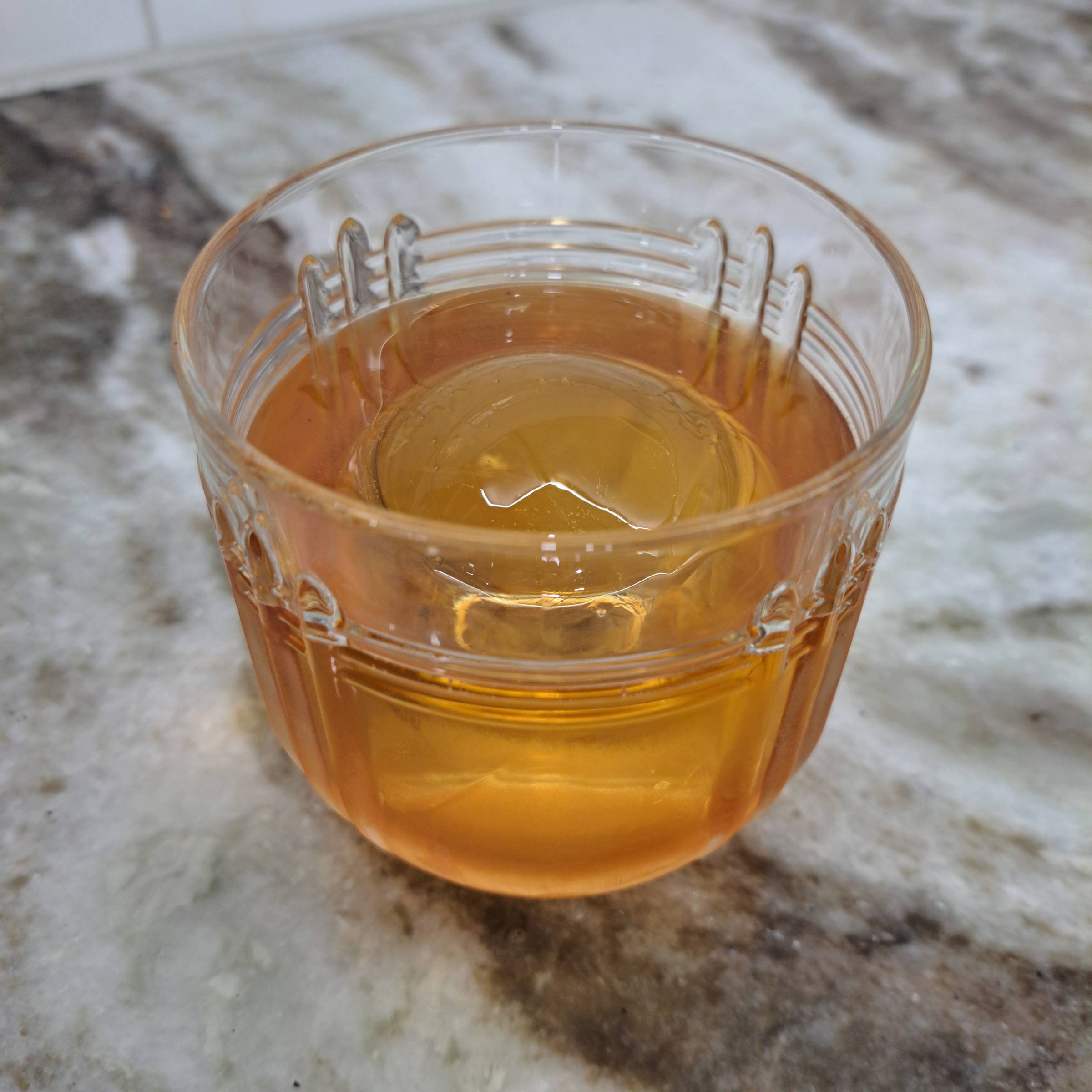 Golden bourbon in a retro glass with a large ice orb