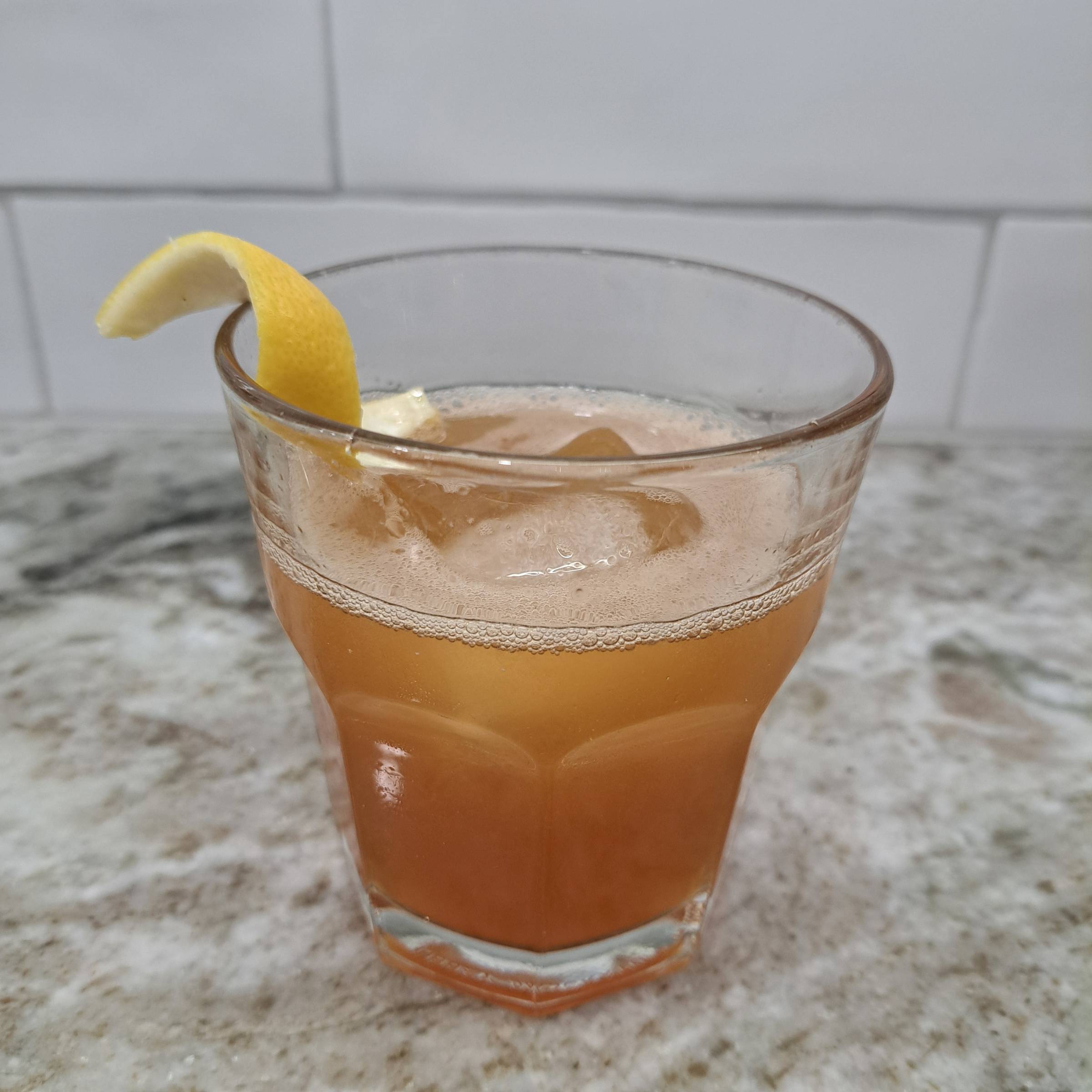 A citrusy cocktail in a glass on a granite countertop