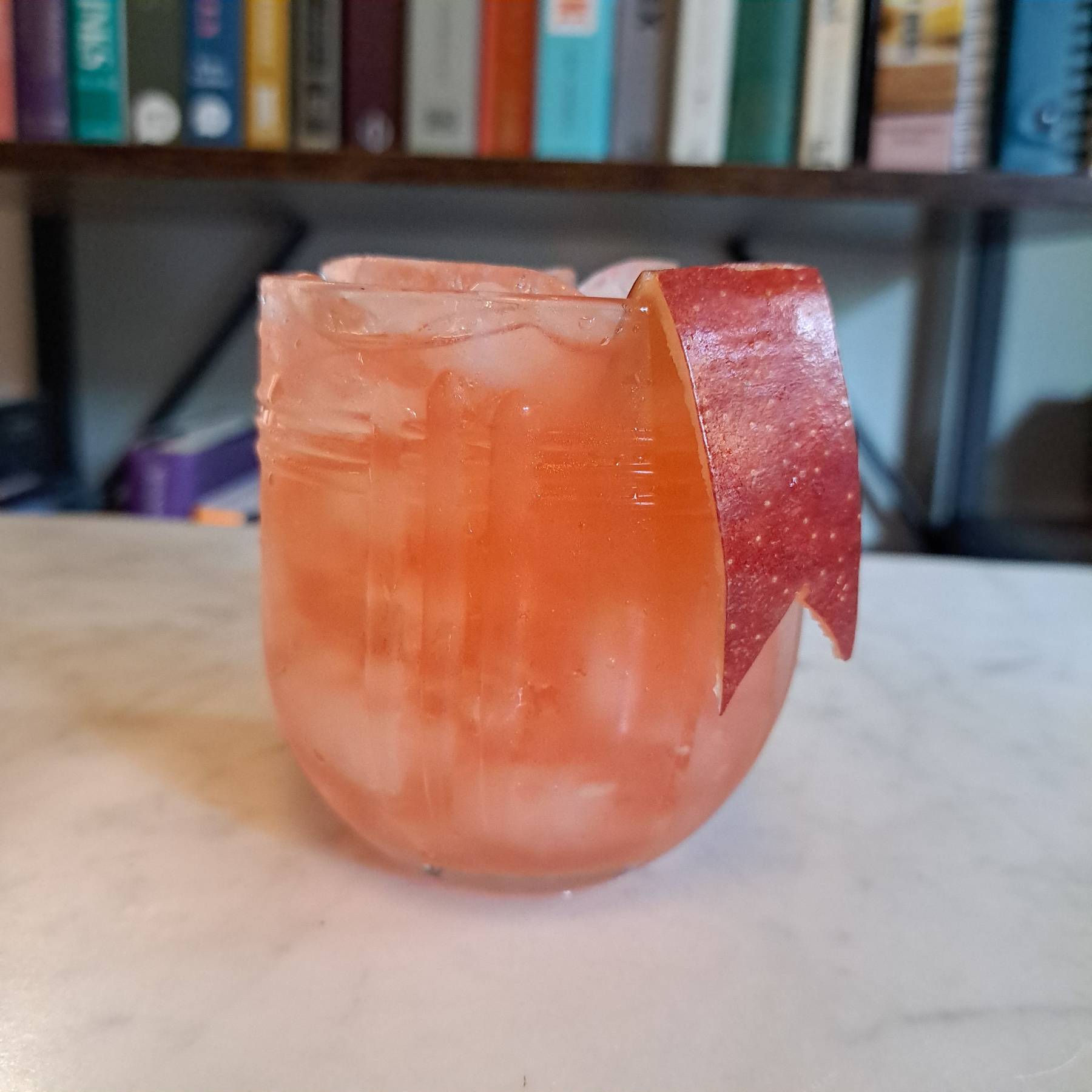 Calvados Daisy cocktail made with Calvados, B&B, lemon juice and grenadine, garnished with apple peel