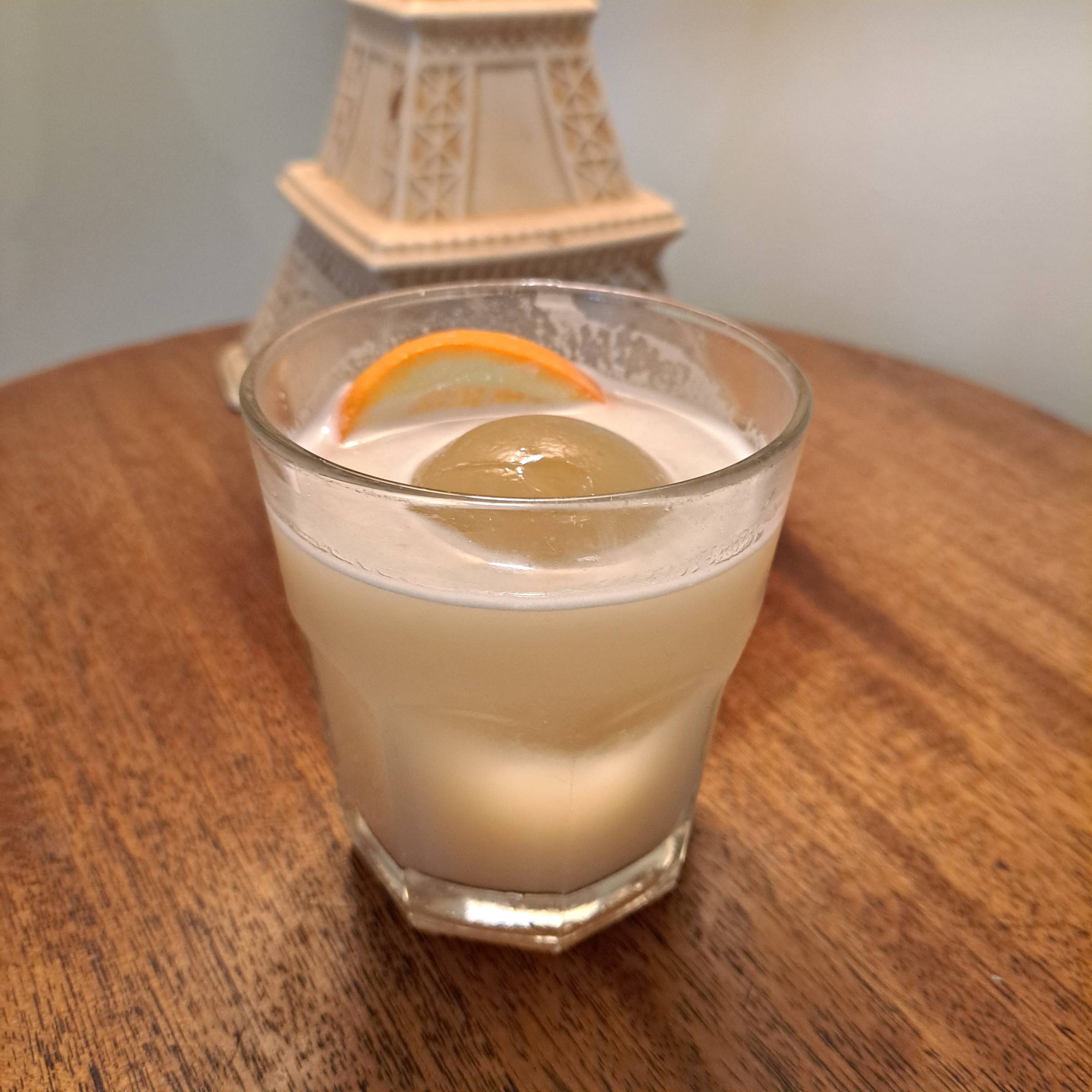 A citrusy cocktail in a glass on a wooden tabletop