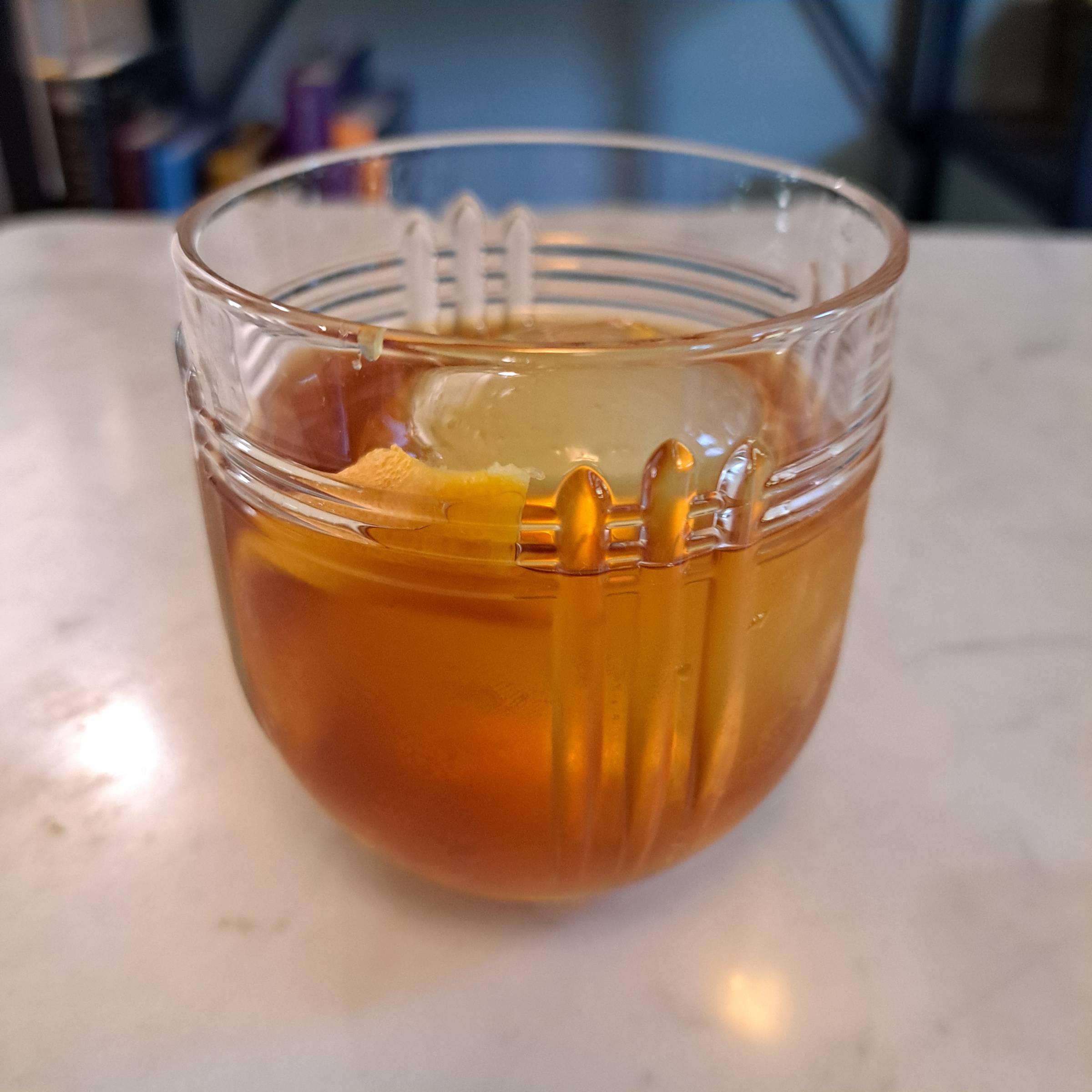 A rich golden cocktail in a Deco-inspired glass on a marble table