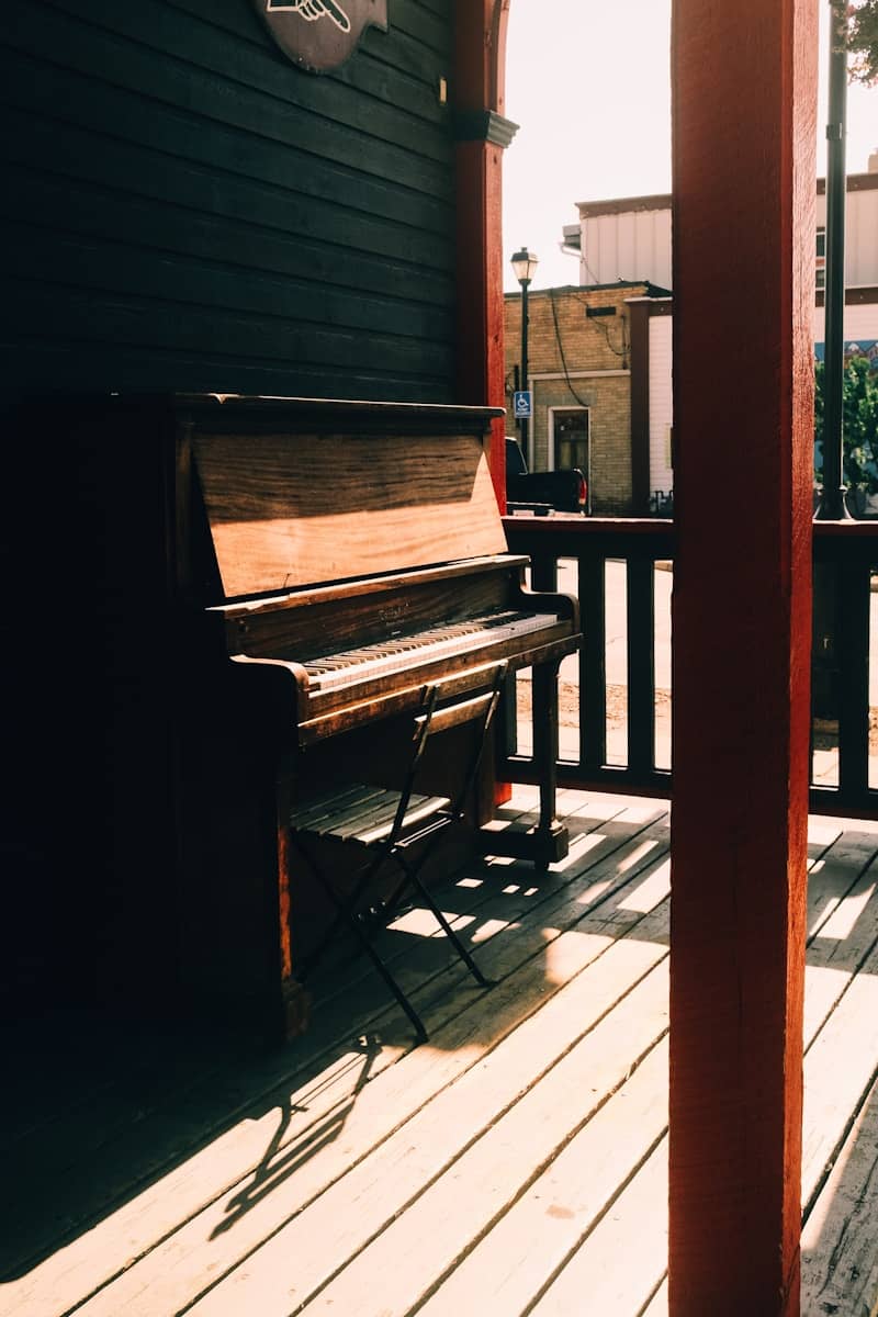 Old upright piano on a wooden deck.
