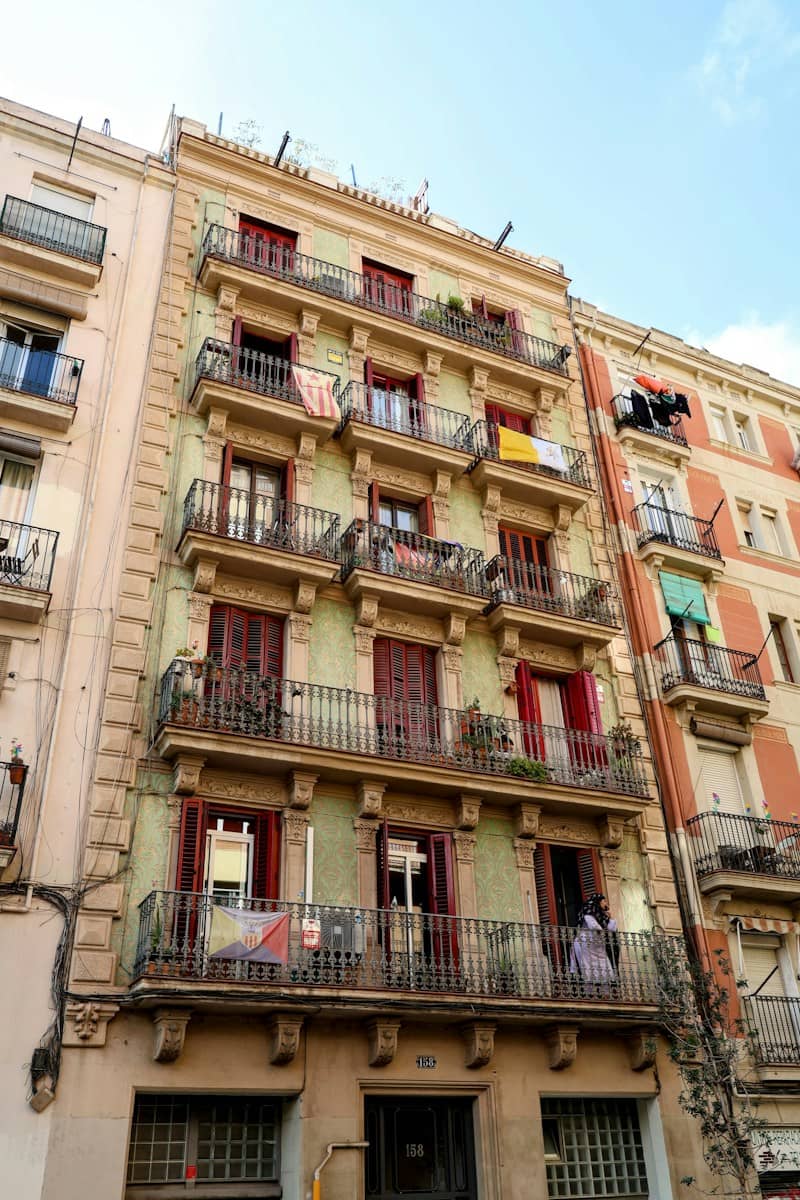 Green-painted apartment building with balconies and clothes drying outside.