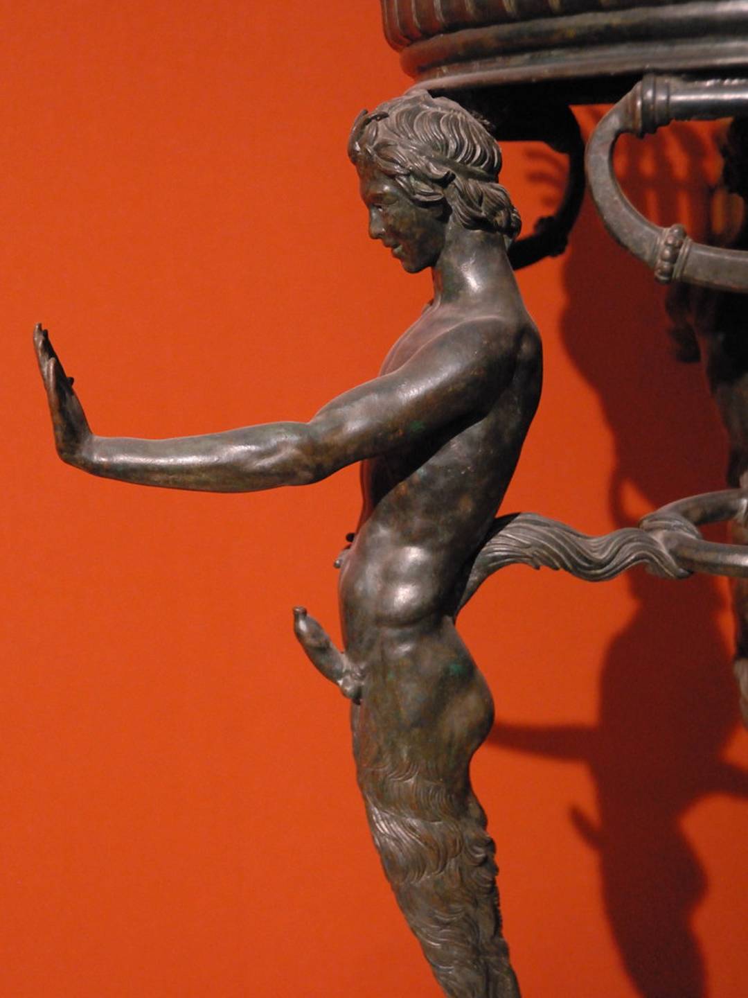 close up of a bronze tripod decorated with a muscular young man sporting a erection