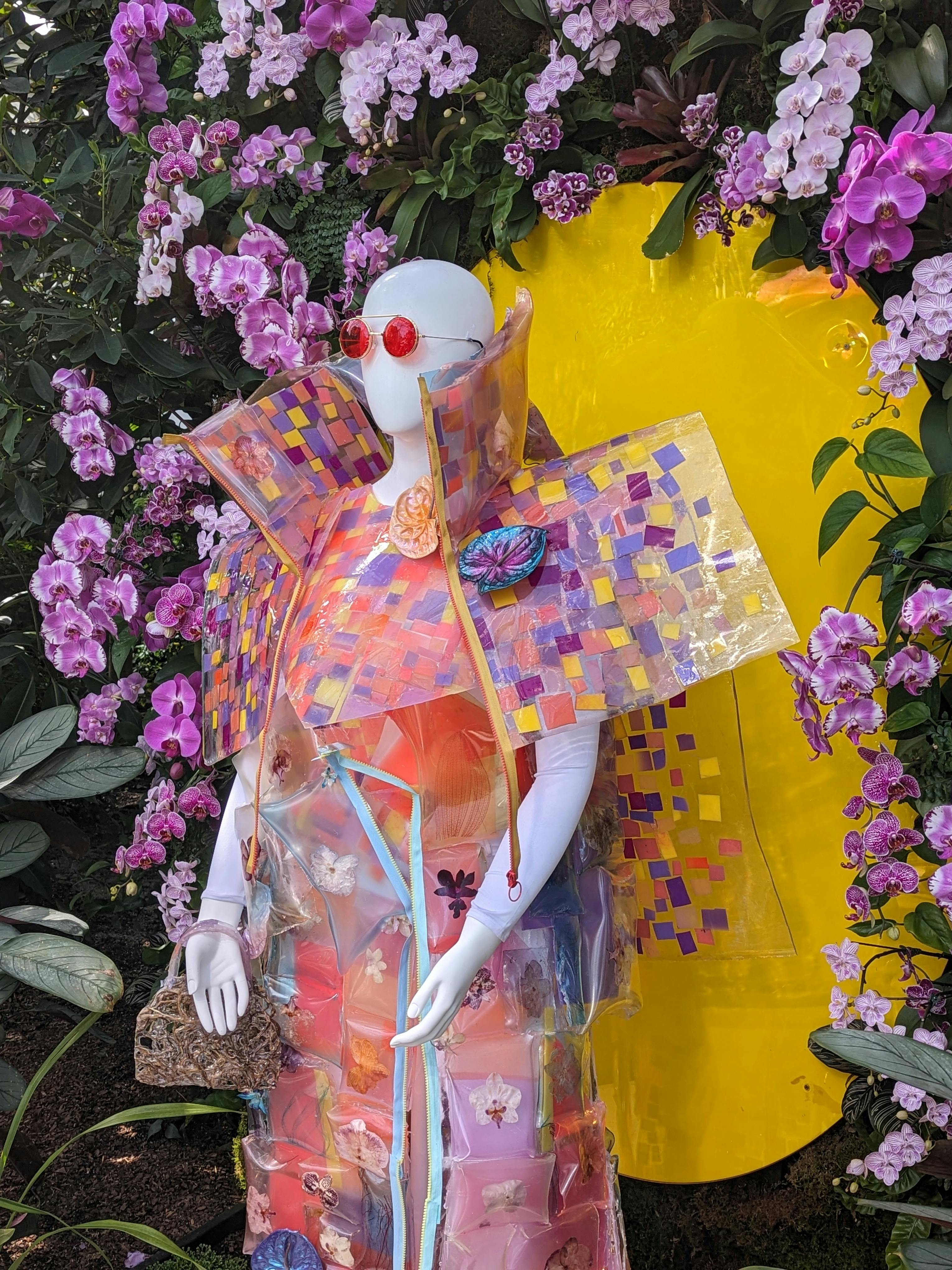 mannequin wearing wild plastic overcoat festooned with flowers