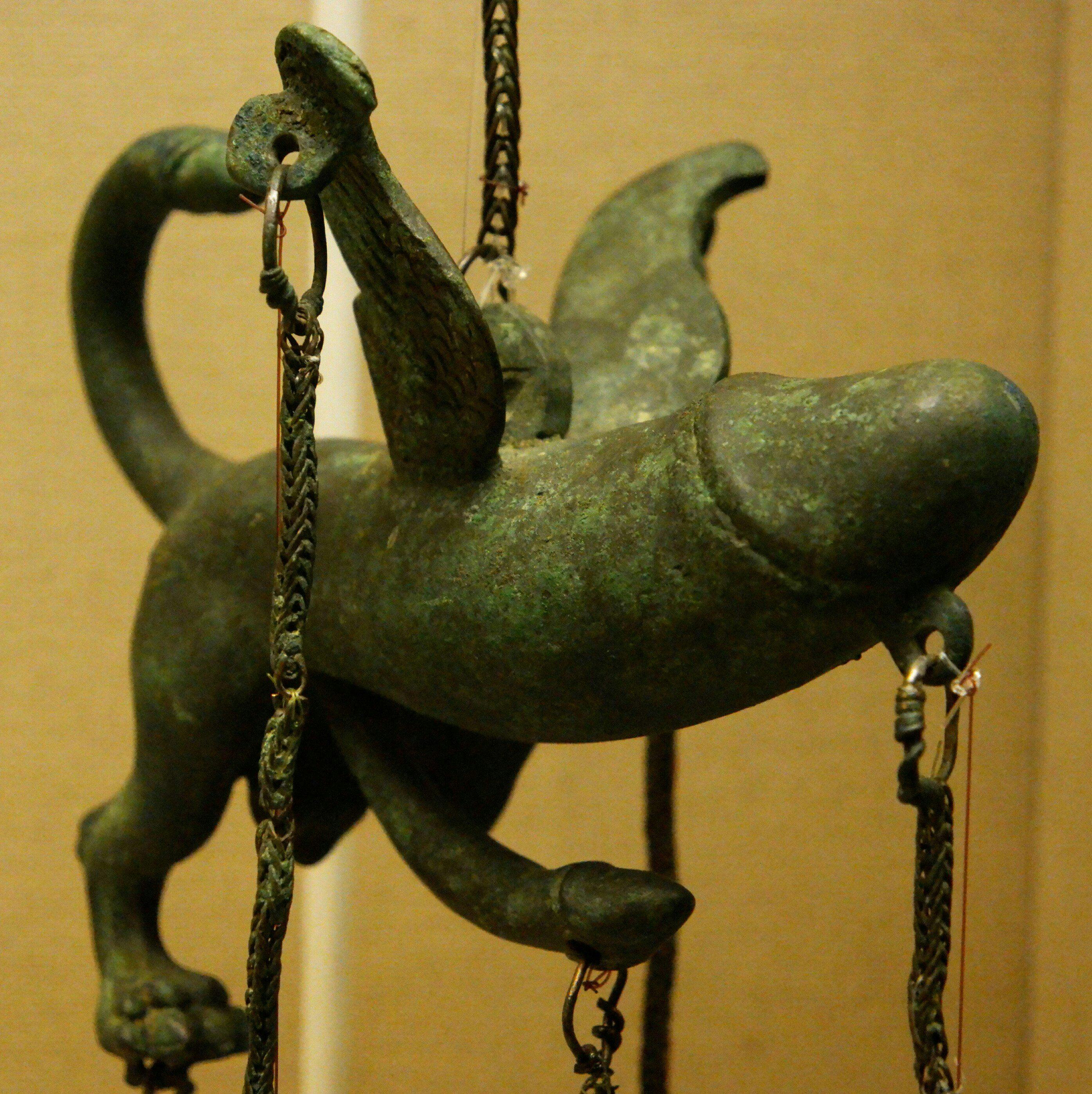 ancient bronze charm that's a giant penis with wings and even the penis has has a penis