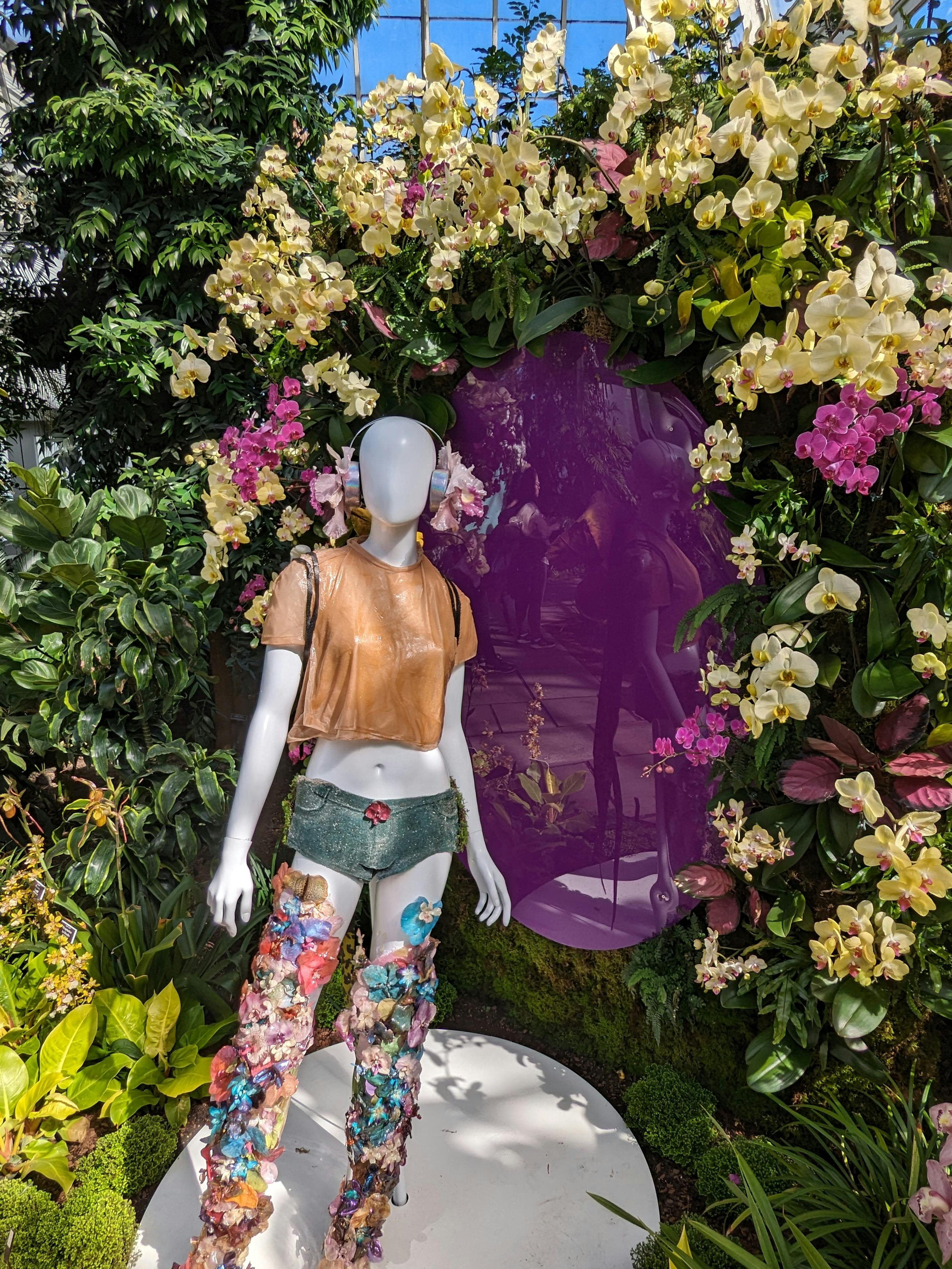 mannequin wearing floral inspired fashion against backdrop of orchids