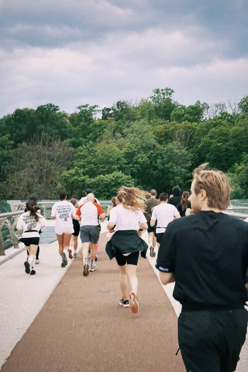 Runners are racing on a path with green trees.