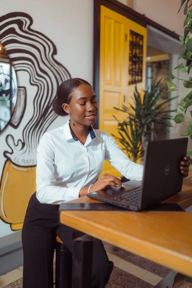 A woman working on a laptop at a wooden table.