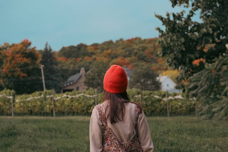 A woman in a red hat walking through a field