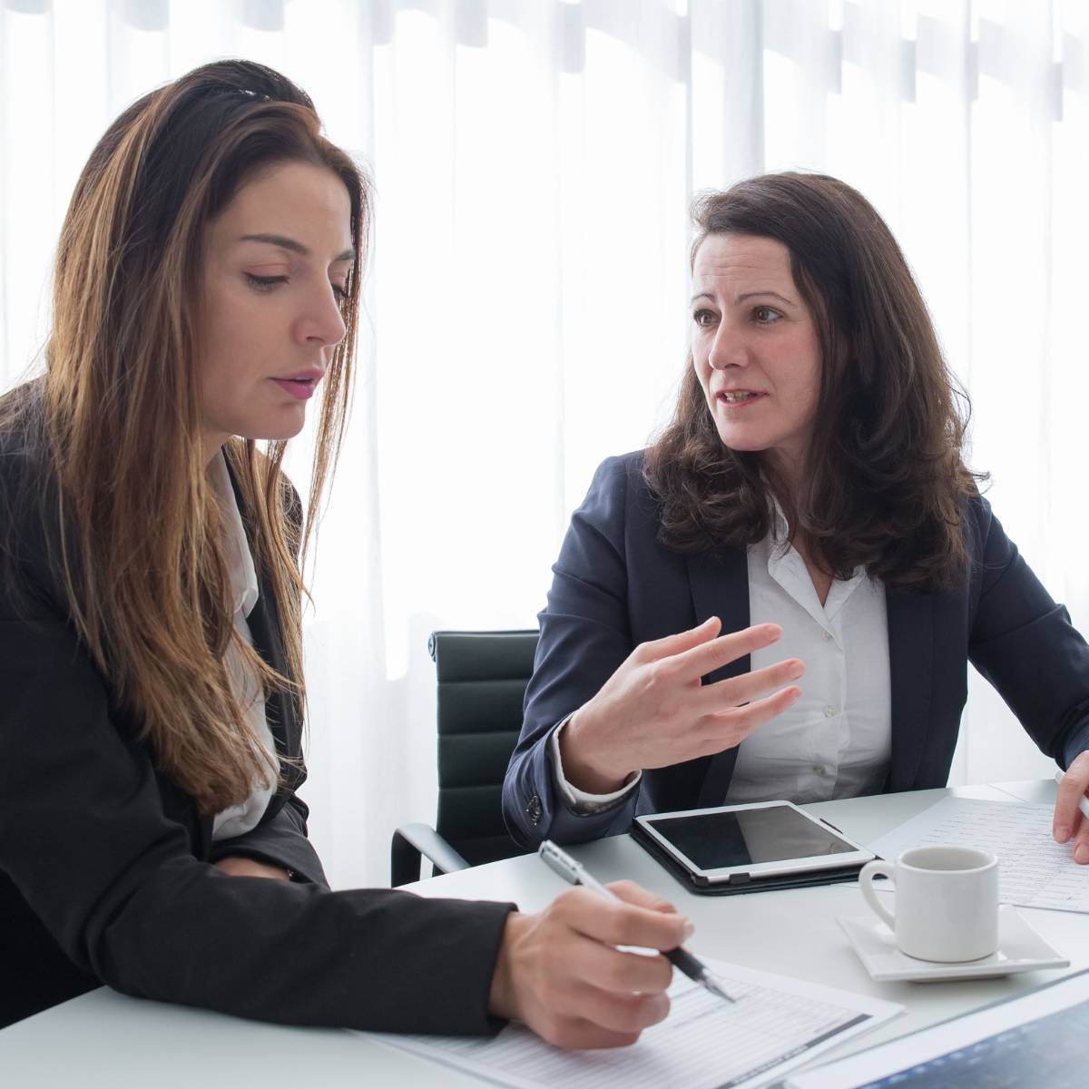 2 business women sitting closely at a table having a personal discussion