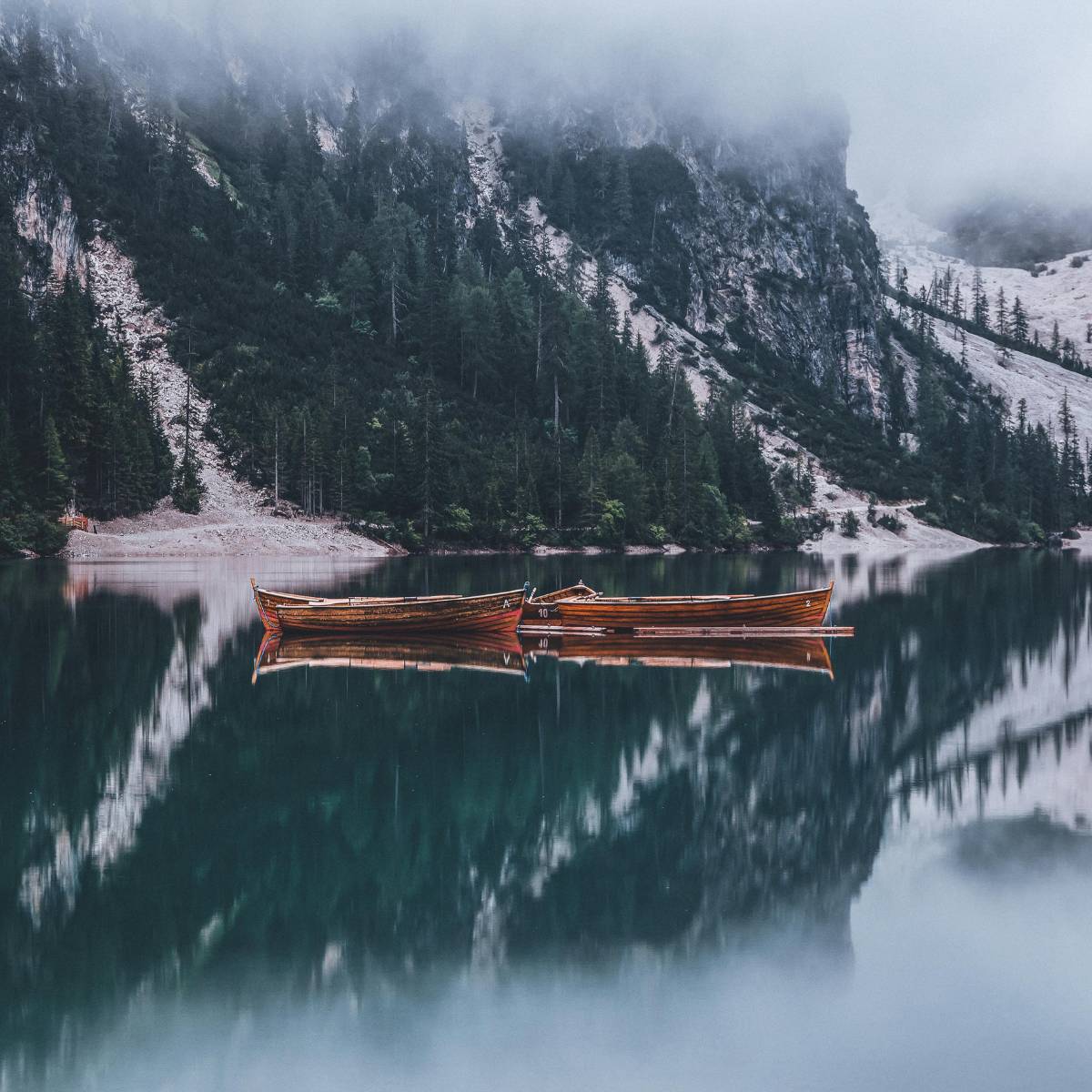 mountain lake with snow, 2 wooden boats float together in the center