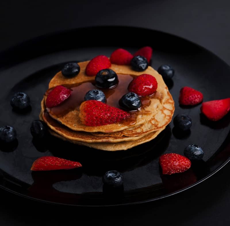 Pancakes with berries and syrup look delicious.