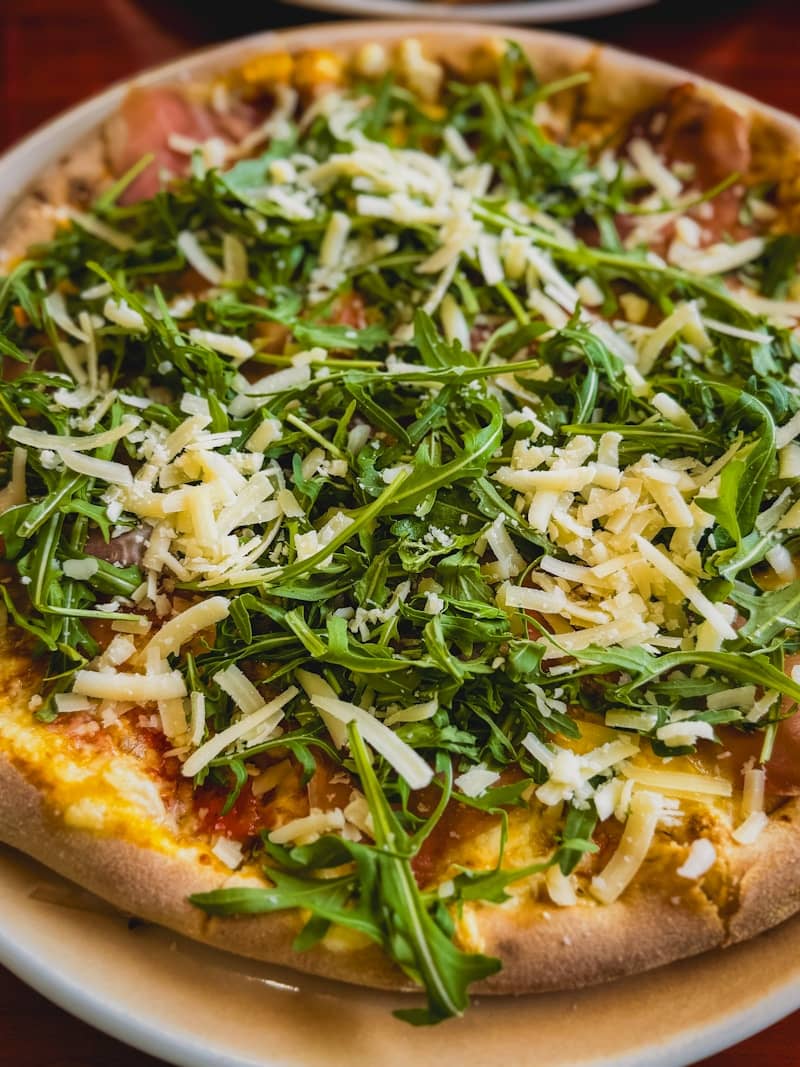 Pizza topped with cheese and fresh greens.