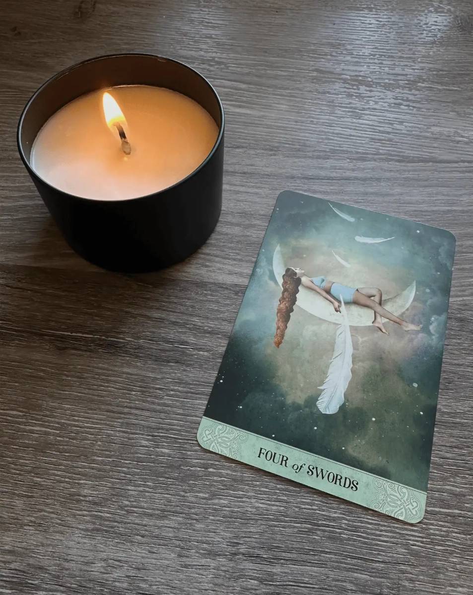 The 4 of swords from Tarot of Mystical Moments shows a woman laying down on the moon while feathers float around her