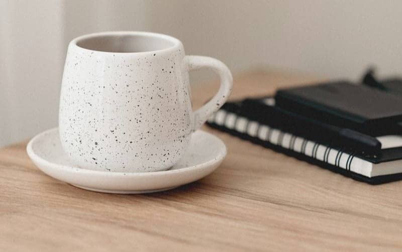 A white coffee cup sitting on top of a wooden table
