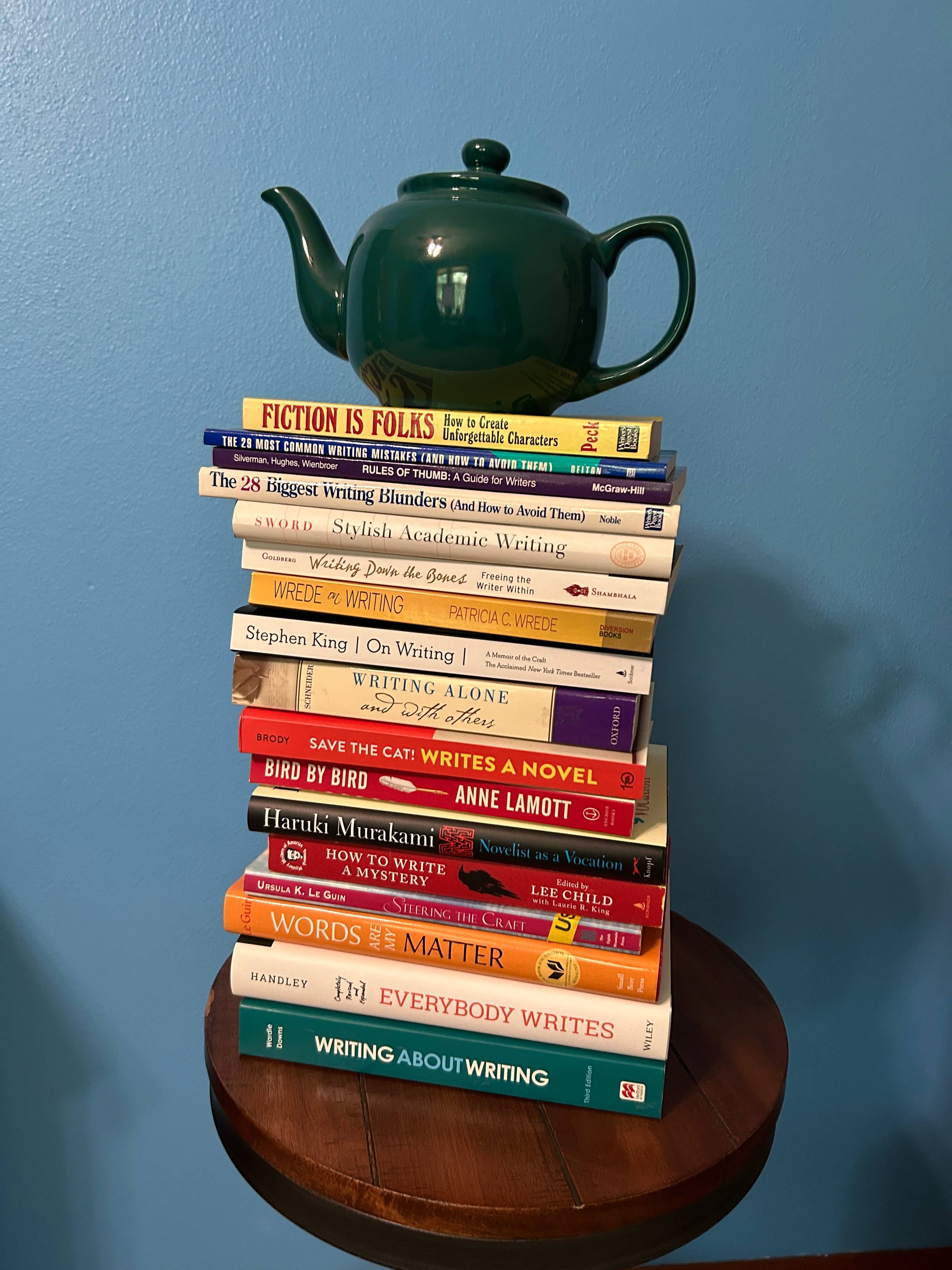 A huge stack of craft books with a teapot sitting on top of them