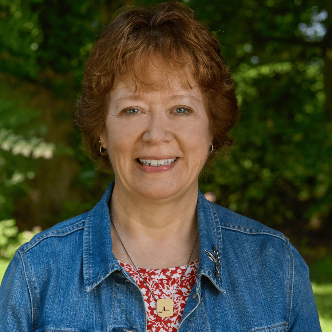 Matty Dalrymple is a white woman with reddish-brown hair. She is wearing a jean jacket and standing outside.