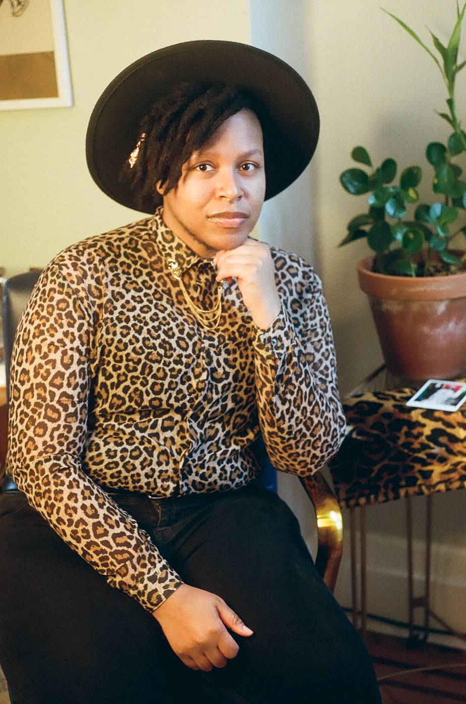 Cyrée is wearing a leopard-print shirt and wearing a black hat with a broad, flat brim