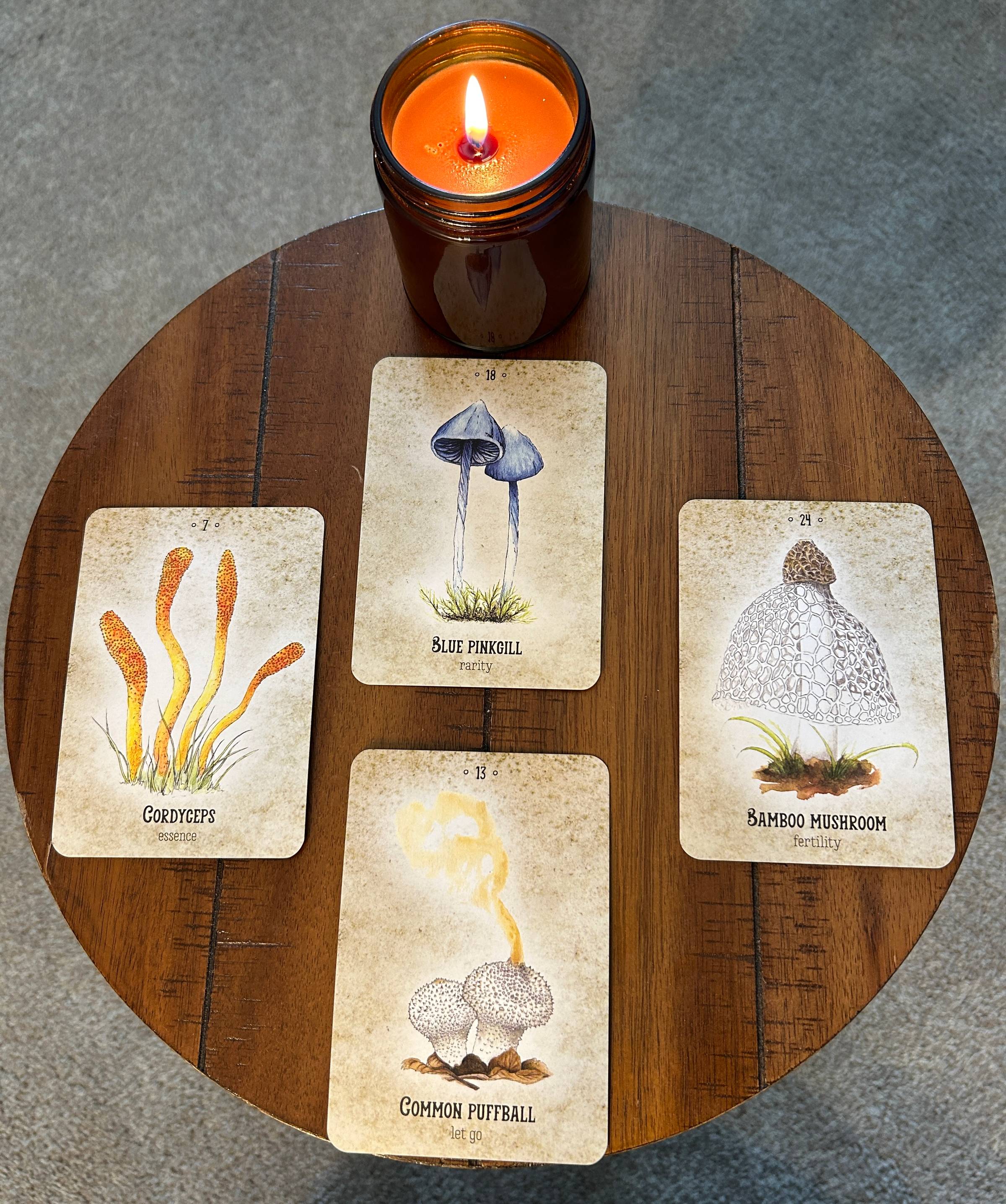 A picture of four oracle cards sitting on a round table. A candle burns at the top of the card layout.