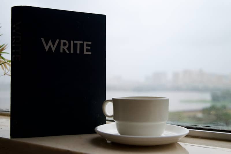 Notebook with the word write and coffee cup by window
