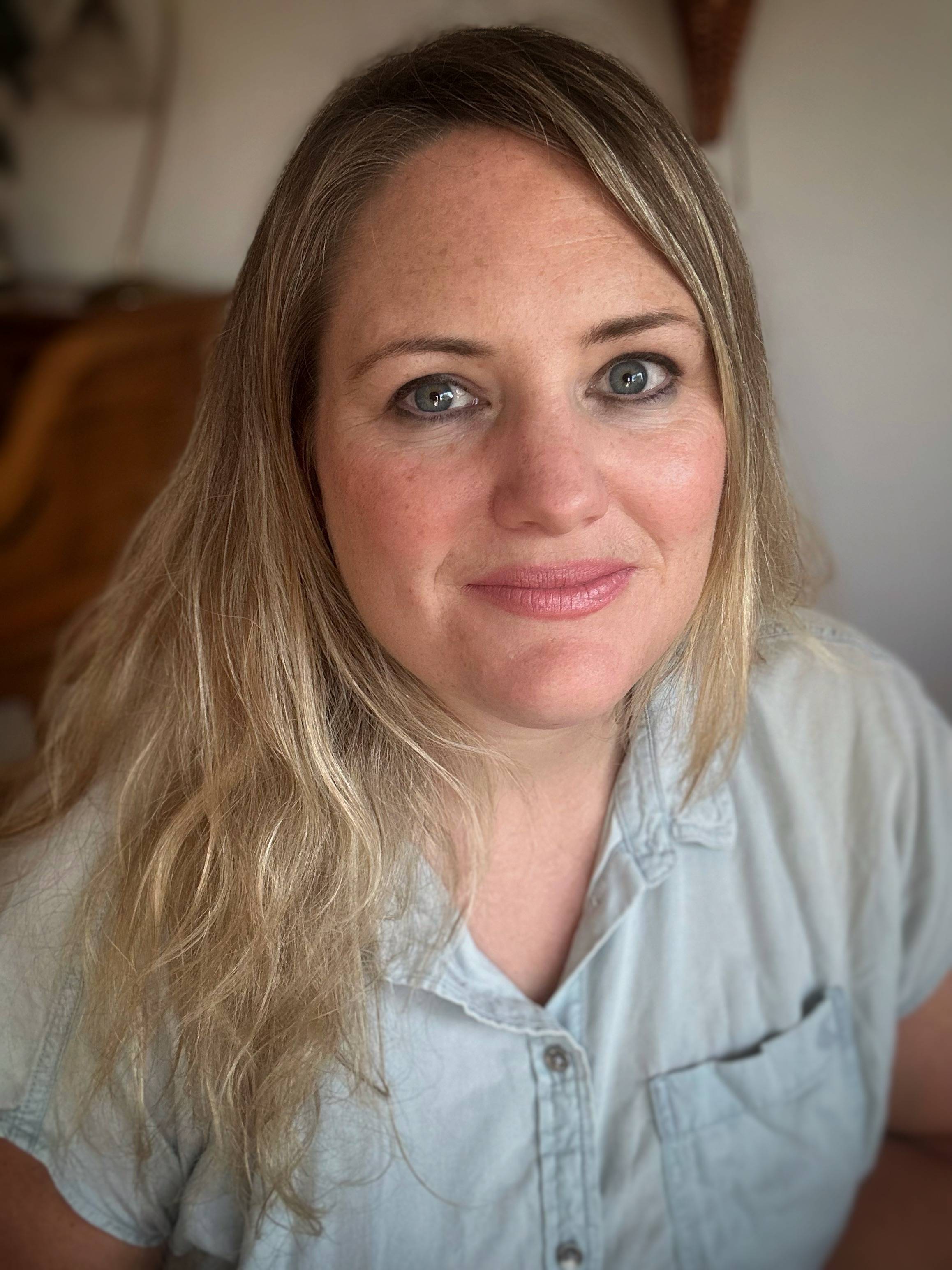 Kasia Van Schaik has blonde hair and is wearing a light denim button-down.