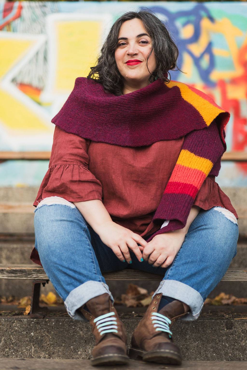 Danette is sitting against a colorful backdrop and smiling at the camera. 