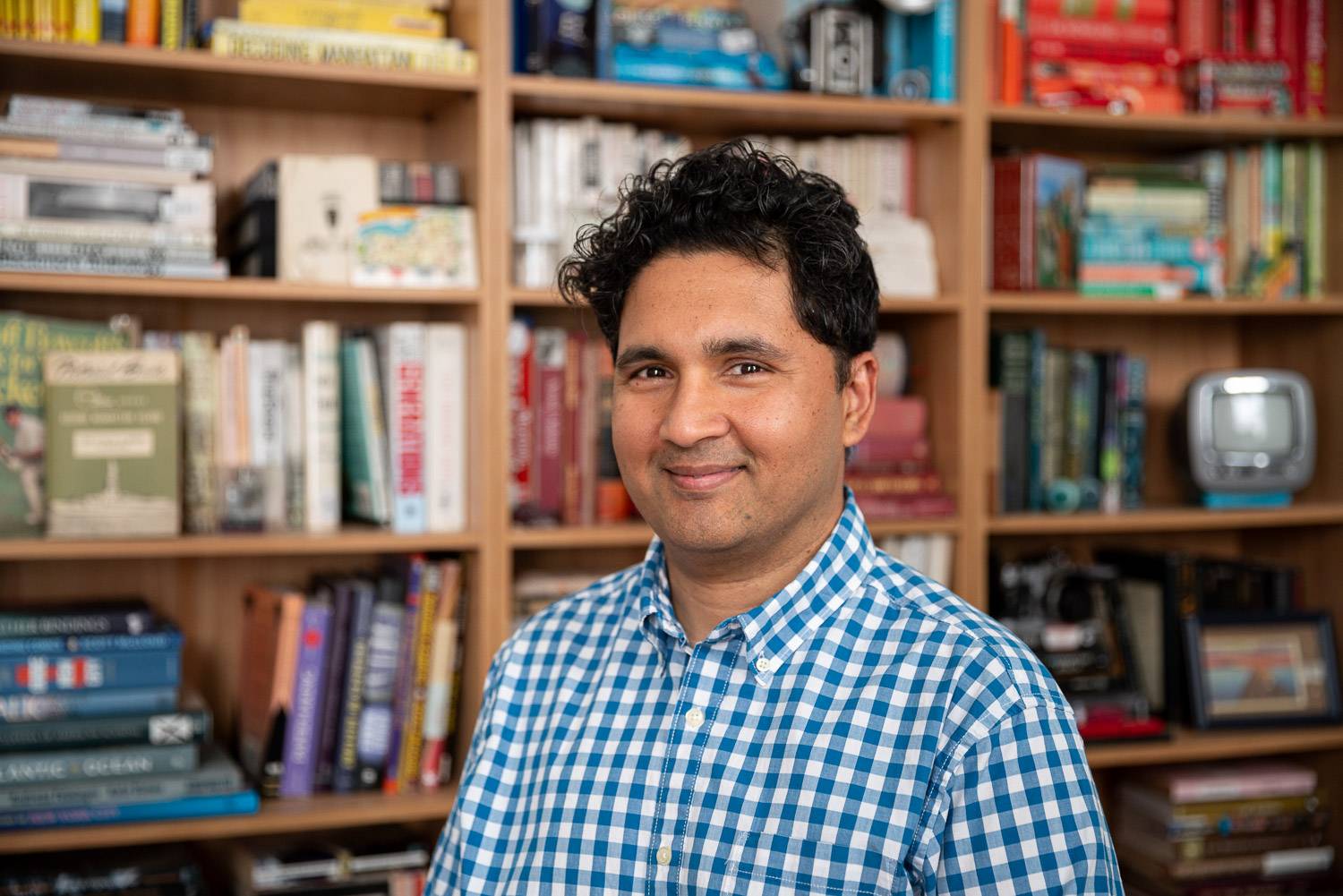 Emon Hassan is smiling in front of a bookshelf.