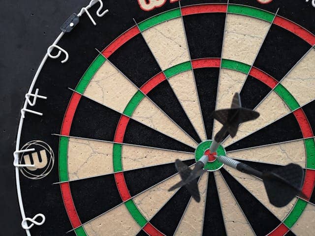 Image of a dart board with three darts sticking out of the bullseye