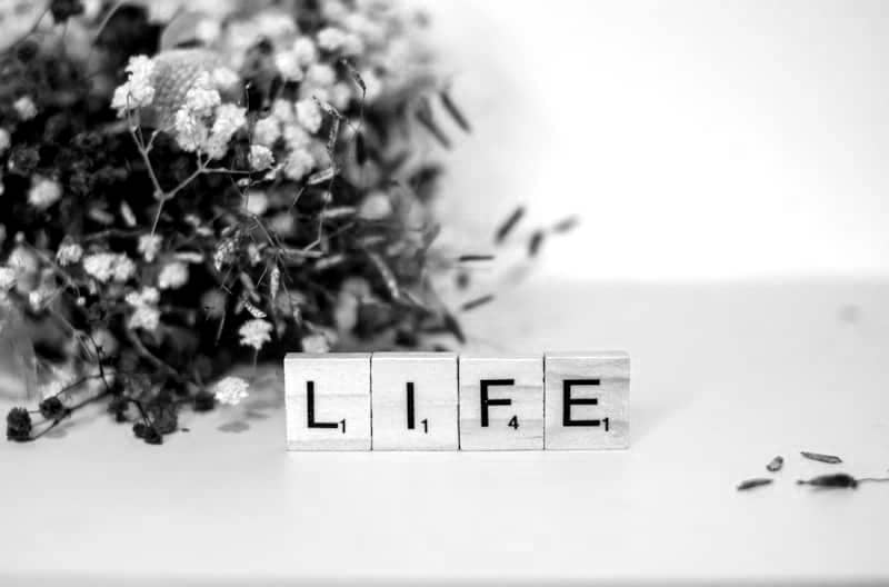 a wooden block that says life next to a bouquet of flowers